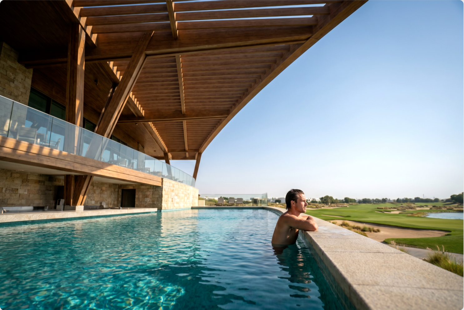 The Greens — infinity pool edge overlooking the golf course with a swimmer